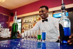 Afroamerikanischer Barkeeper an der Bar, der Cocktails auf Aufnahmen macht. Zubereitung von alkoholischen Getränken. foto