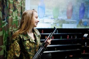 Mädchen mit Maschinengewehr an den Händen auf dem Schießstand. foto