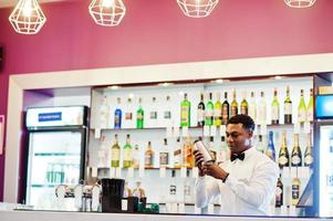 Afroamerikanischer Barkeeper an der Bar mit Shaker. Zubereitung von alkoholischen Getränken. foto