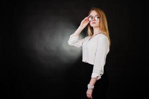 Studioporträt einer blonden Geschäftsfrau mit Brille, weißer Bluse und schwarzem Rock vor dunklem Hintergrund. erfolgreiche frau und stilvolles mädchenkonzept. foto