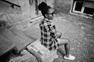 Hip-Hop-Afroamerikanermädchen auf Sonnenbrillen und Jeans-Shorts. Lässiges Straßenmodeporträt einer schwarzen Frau. foto