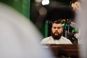 hübscher bärtiger mann im friseursalon, friseur bei der arbeit. foto