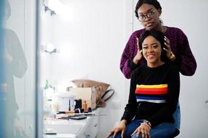 Afroamerikanerin beim Schminken durch Make-up-Künstlerin im Schönheitssalon. foto