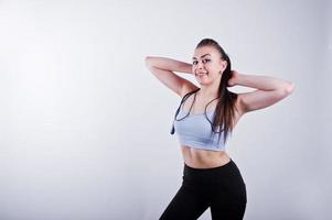 Fröhliche attraktive junge Fitness-Frau in Top und schwarzen Leggings mit Springseil isoliert auf weißem Hintergrund. foto