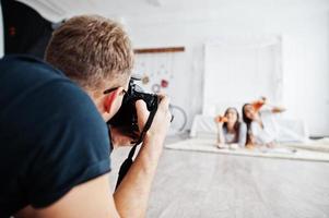 Mann Fotograf schießt auf Studiozwillinge Mädchen, die Pizza essen. professioneller fotograf bei der arbeit. foto