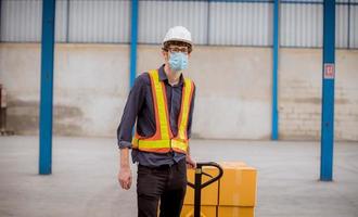 werksingenieur wird inspiziert und überprüft den qualitätsproduktionsprozess auf der herstellungsstation für gesichtsmasken, indem er auf der fabrikplantage eine lässige uniform und einen schutzhelm trägt. foto