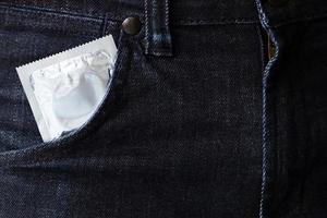 Kondom gebrauchsfertig in Pocket-Jeans-Hose geben Safer-Sex-Konzept auf dem Bett Ansteckung verhindern und Verhütungsmittel die Geburtenrate kontrollieren oder sicher prophylaktisch sein. Welt-AIDS-Tag, foto