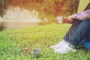 Wandern Mann Rucksacktouristen sitzen vor Zelt Camping durstig Mann mit einer Pause gießt Wasser trinken aus einer Stahlwasserflasche. abenteuer-, reise- und tourismuskonzept foto