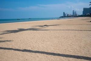 Strand am Nachmittag. Stadt und Gebäude auf der anderen Seite. Kokospalmenschatten lag am Strand. foto