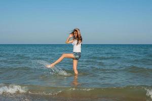 junges Mädchen, das das Wasser im Meer spritzt foto