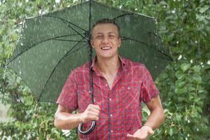 Mann mit Regenschirm im Regen foto