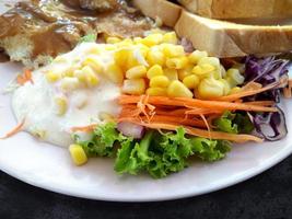 steakfisch mit salat und geröstetem brot auf teller, draufsichtwurst und gemüse im hintergrund foto
