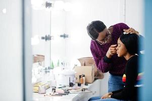 Afroamerikanerin beim Schminken durch Make-up-Künstlerin im Schönheitssalon. foto