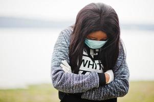 afrikanisches mädchen im park, das medizinische masken trägt, schützt vor infektionen und krankheiten coronavirus-virus-quarantäne. foto