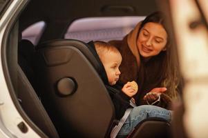 junge Mutter und Kind im Auto. Kindersitz auf Stuhl. Fahrsicherheitskonzept. foto