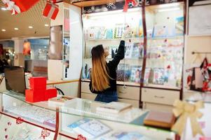 Porträt des jungen kaukasischen weiblichen Verkäufers. kleines Geschäft mit Süßigkeiten-Souvenir-Shop. foto