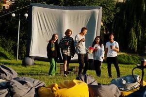 junge multiethnische gruppe von menschen, die filme im poof im open-air-kino ansehen. foto