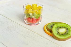 Diät frischer leckerer Obstsalat in einem Glas auf Holztisch. gehackte saftige Orangen, Kiwis und Grapefruits. foto
