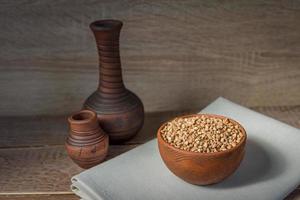 Trockener Buchweizen in brauner Tonschale auf Holztisch. glutenfreies getreide für eine gesunde ernährung foto