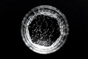Draufsicht auf Sprudelwasser in transparentem Glas auf schwarzem Hintergrund. foto