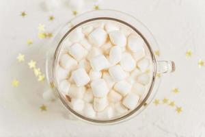Draufsicht auf eine Tasse heißes, köstliches Kakaogetränk mit Marshmallows auf goldenem Sternenhintergrund foto
