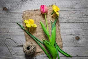 Draufsicht auf Frühlingsblumenstrauß. gelbe narzissen und rosa tulpe auf holzhintergrund. Platz kopieren. foto