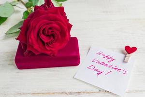 Schmuck-Geschenkbox und wunderschöne rote Rose auf Holzhintergrund. Geschenk zum Valentinstag foto