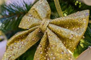 weihnachts- und neujahrsferienhintergrund. weihnachtsbaum geschmückt mit goldfunkelnder schleife. feierkonzept foto