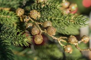 nahaufnahme des weihnachtsbaums, der mit goldenen kleinen kugeln geschmückt ist. hintergrund des neuen jahres foto