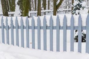 Winter auf dem Land. Blauer Holzzaun mit Schnee bedeckt. Schneefall und Schneewehe. foto