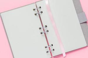 Nahaufnahme eines offenen leeren Notizbuchs mit Einband aus Recyclingpapier auf pastellrosa farbigem Hintergrund foto