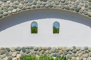 weiße wand mit steinen verziert mit zwei fenstern mit blick auf die naturlandschaft foto