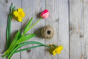 Draufsicht auf Frühlingsblumenstrauß. gelbe narzissen und rosa tulpe auf holzhintergrund. Platz kopieren. foto