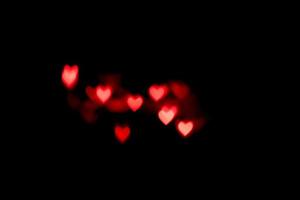rosa Herzen Bokeh auf schwarzem Hintergrund. festliche Textur für Feiertage foto