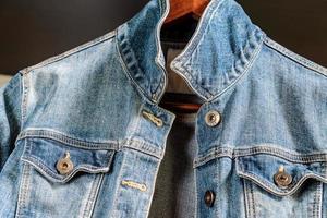 Blaue Jeansjacke auf einem Holzbügel. trendige Kleidung. foto