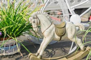 Statue eines Pferdes aus weißem Ton in der Nähe von grünen Pflanzen in geflochtenen Töpfen. gartendekoration anordnung foto