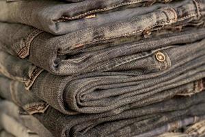 Stapel blaue Jeans auf Holzregal mit Kopierraum. Schönheits- und Modekleidungskonzept, selektiver Fokus foto