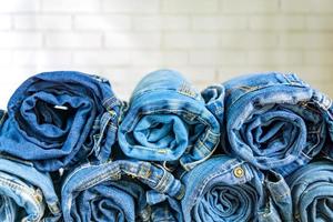 Rollen Sie blaue Denimjeans, die im Stapel auf Wandhintergrund angeordnet sind. Schönheits- und Modekleidungskonzept foto