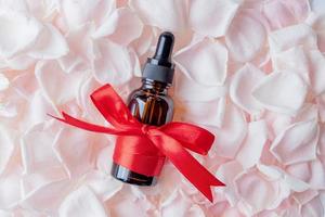 kosmetisches Serum mit ätherischem Rosenöl und Rosenblättern. Naturprodukt zur Entgiftung, Befeuchtung, Straffung und Regeneration der Haut. markenloses Produktmodell foto