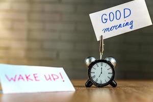 Wecker und Banner mit handgeschriebenem guten Morgen auf Holztisch. Zeitmanagement-Konzept. foto