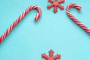 Grußkarte der frohen Weihnachten und des guten Rutsch ins Neue Jahr. Zwei Zuckerstangen und funkelnde Schneeflocken auf blauem Hintergrund mit Kopierplatz für Ihren Text. foto