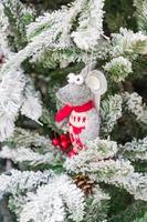 symbol des jahres 2020. weiße spielzeugratte in weihnachtsmütze, die am schneebedeckten pelzbaum hängt. festliche Innendekoration.