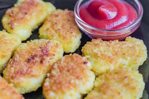 Gebratene knusprige Chicken Nuggets mit Ketchup auf einem schwarzen Teller foto