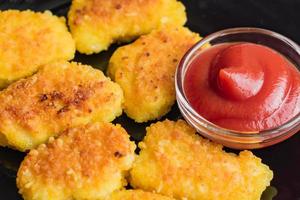 Gebratene knusprige Chicken Nuggets mit Ketchup auf schwarzem Teller. ungesundes Essen. foto