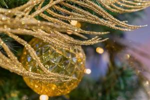 weihnachts- und neujahrsferienhintergrund. weihnachtsbaum verziert mit goldkugel und funkelnder feder. feierkonzept foto