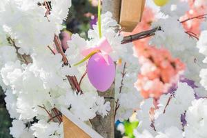 Rosa Osterei hängt an blühendem Apfelbaumzweig. osterdekoration und feierkonzept. foto