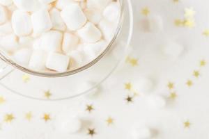 Draufsicht auf eine Tasse heißes, köstliches Kakaogetränk mit Marshmallows auf goldenem Sternenhintergrund foto