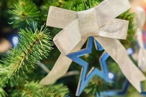 weihnachts- und neujahrsferienhintergrund. weihnachtsbaum verziert mit silberner schleife und blauem stern. feierkonzept foto