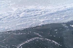 eisige wasseroberfläche mit rissen und eisschollen foto