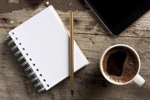 Tablet, Telefon, Notizblock und Kaffee auf Holztisch